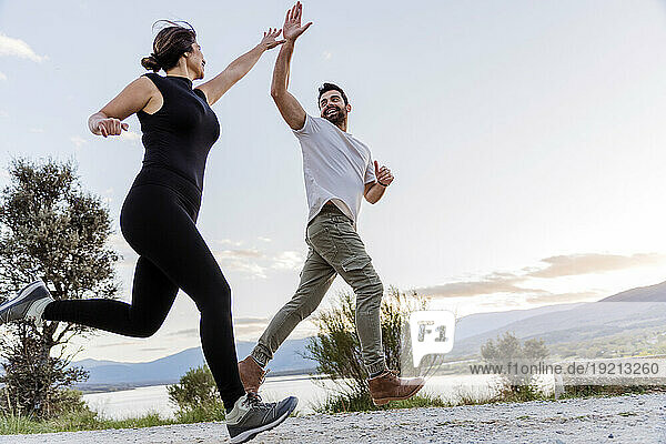 Couple giving high-five and running on footpath