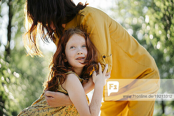 Redhead daughter hugging mother in park