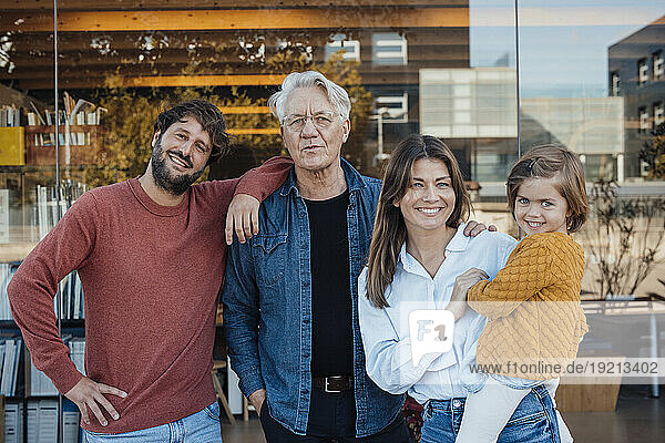 Smiling man standing with family in front of glass wall