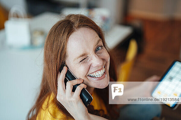 Happy woman talking on phone at home