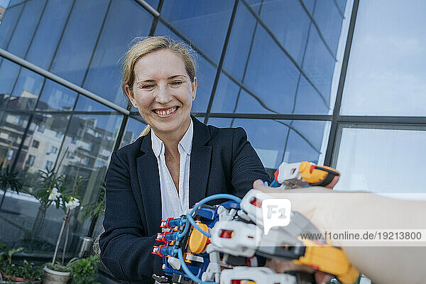 Happy architect looking at robotic arm near office building