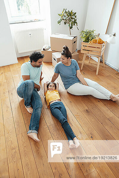 Happy parents with daughter lying on floor at home