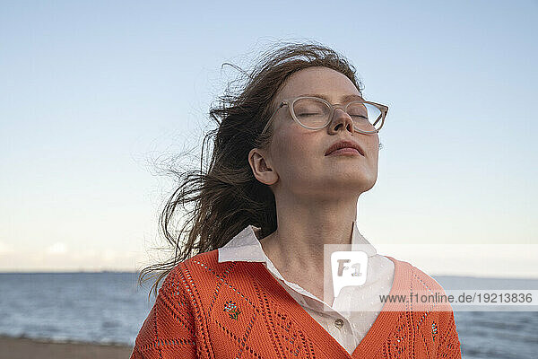 Young woman with eyes closed in front of sea