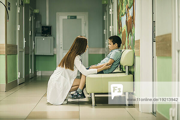 Female doctor consoling boy at medical clinic