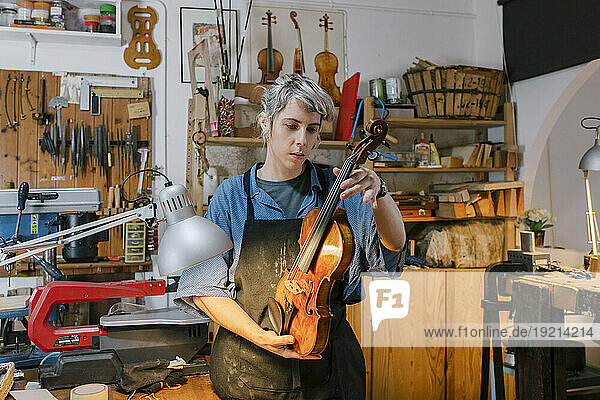 Luthier examining violin in workshop