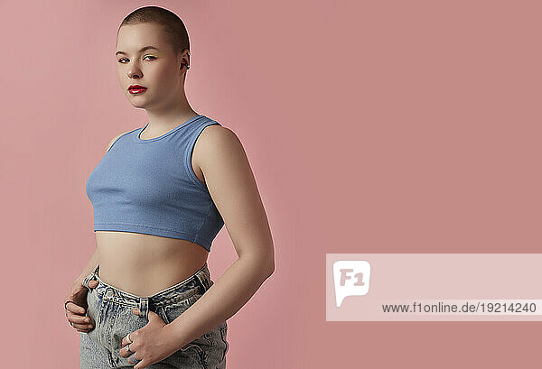 Young woman posing against pink background