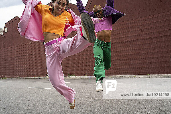 Cheerful couple jumping and having fun together in front of building