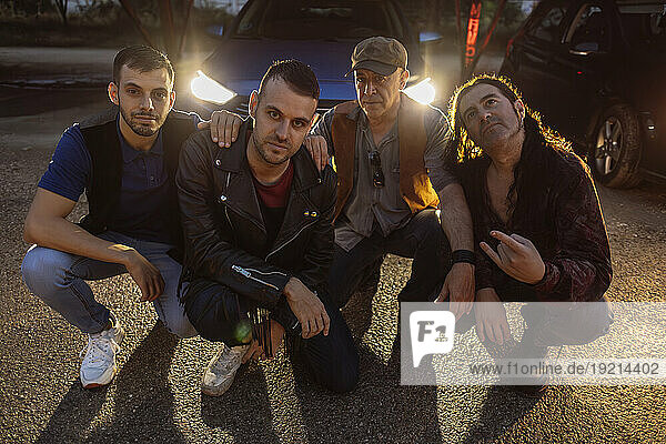 Friends with attitude crouching together in front of car