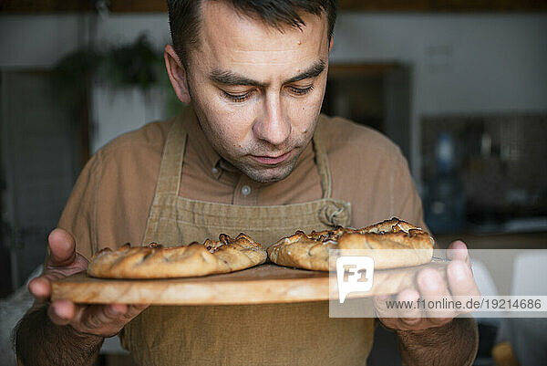 Man smelling baked pie on cutting board
