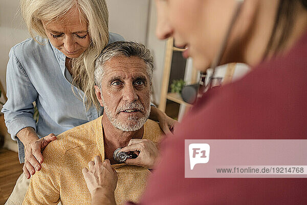 Doctor examining mature patient at home