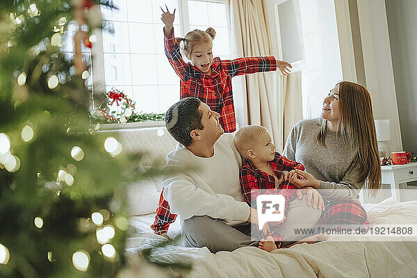 Family looking at daughter dancing on bed