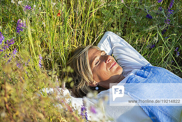 Woman with eyes closed relaxing in meadow