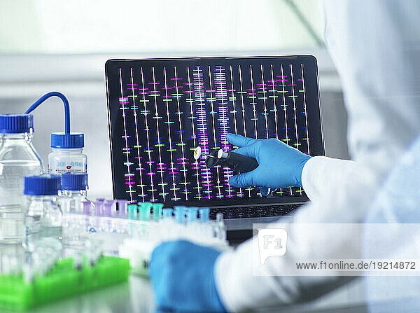 Scientist reviewing DNA information on laptop in laboratory