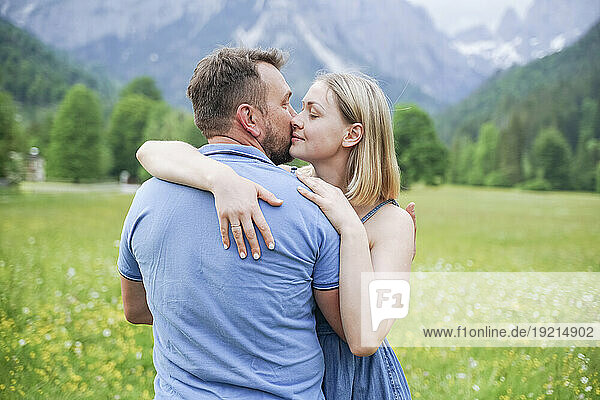 Affectionate man kissing woman in front of mountains