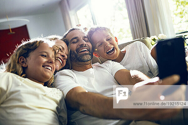 Happy man taking selfie with family on smart phone at home