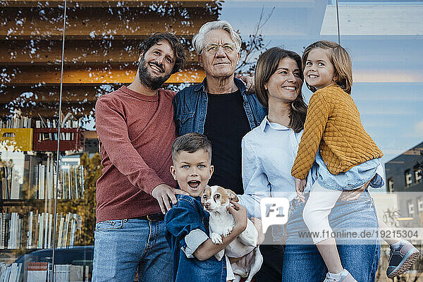 Happy family with dog in front of glass wall