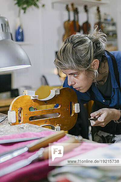 Luthier working on violin in musical instrument workshop