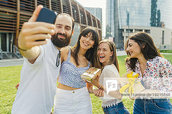 Lächelnder Mann  der mit Freunden ein Selfie per Smartphone macht