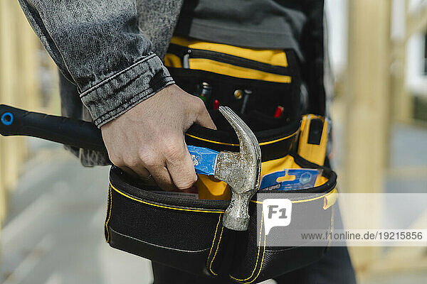 Engineer wearing tool belt holding hammer in hand
