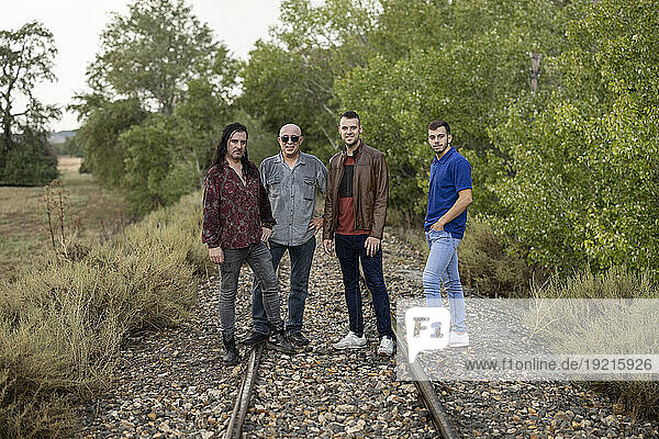 Friends standing on railroad tracks amidst plants