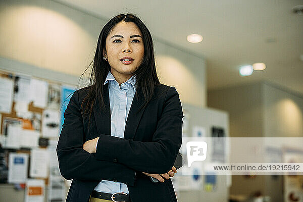 Beautiful businesswoman standing with arms crossed in office