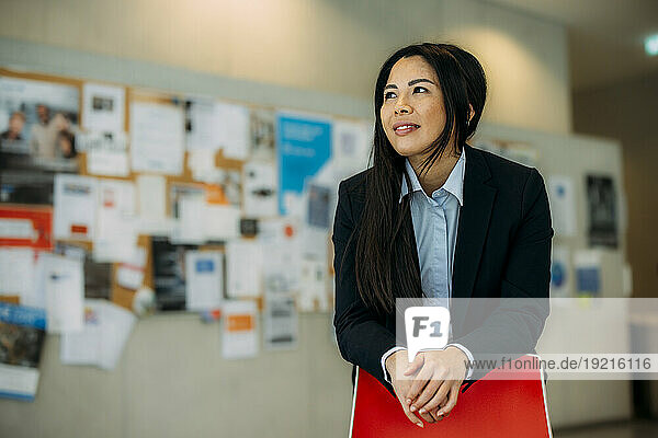 Smiling businesswoman leaning on chair at office