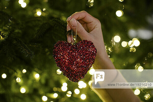 Hand of woman holding heart shaped Christmas decoration