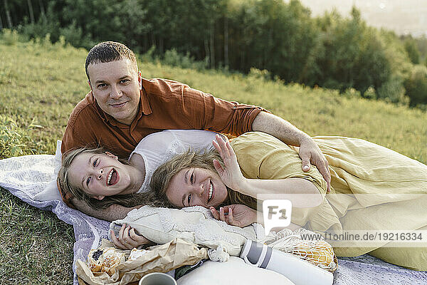 Happy family having fun and lying on blanket in meadow