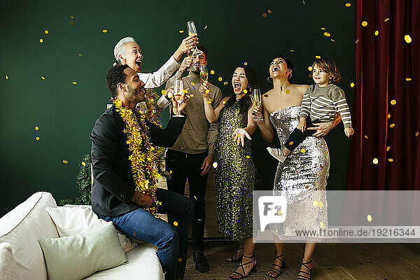 Happy family with champagne glasses enjoying amidst falling confetti at home
