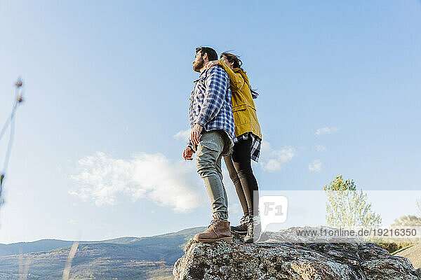 Couple standing on rock under sky