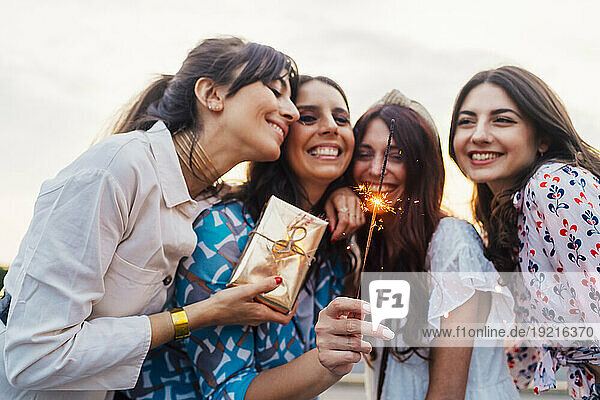 Cheerful friends with gift box and sparkler