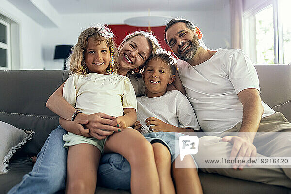 Happy parents with children sitting on sofa at home