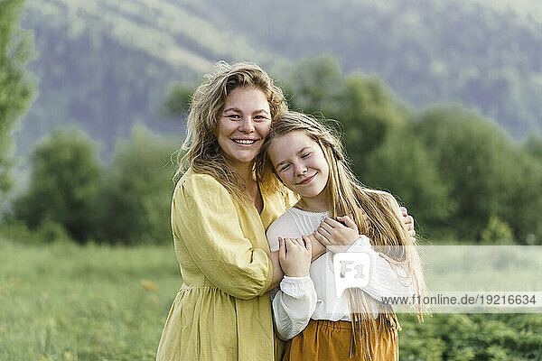 Happy mother and daughter embracing in meadow