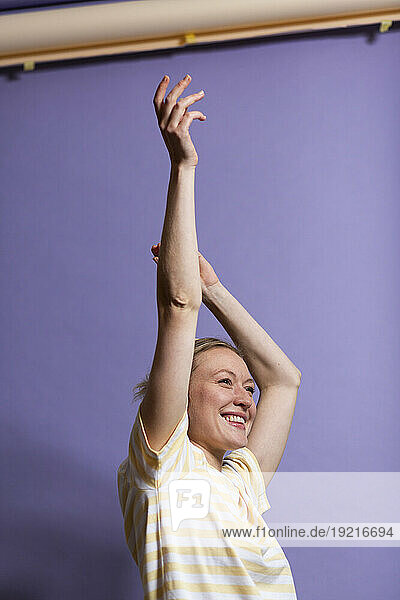 Happy woman with arms raised enjoying in studio