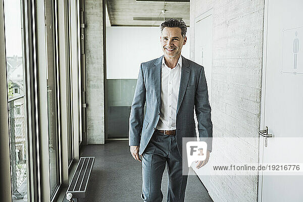 Happy mature businessman walking in office corridor