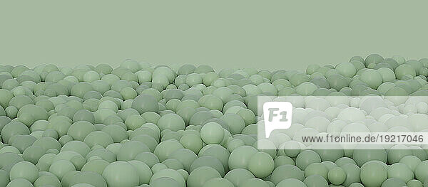 Pastel green spheres over colored background in studio