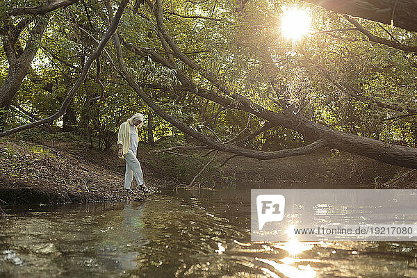 Mature woman at riverbank in forest