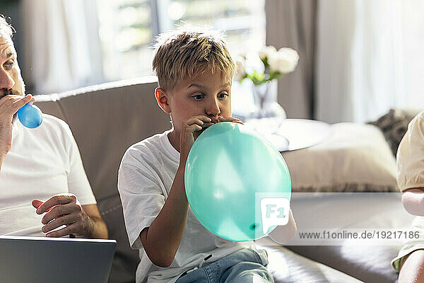 Boy blowing balloon with father at home