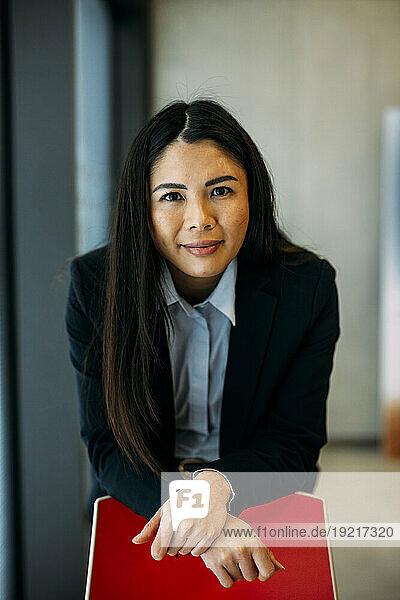 Smiling beautiful businesswoman leaning on chair at office