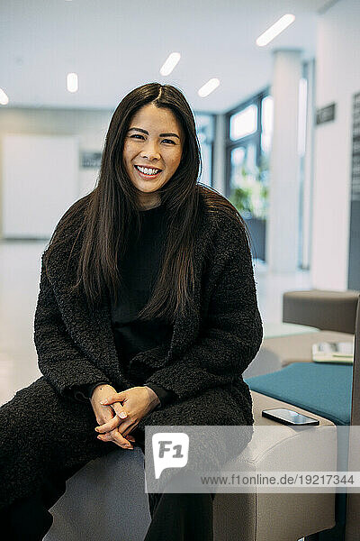 Smiling beautiful businesswoman sitting with hands clasped at office