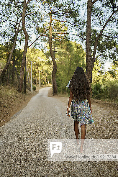 Teenage girl walking on road in forest