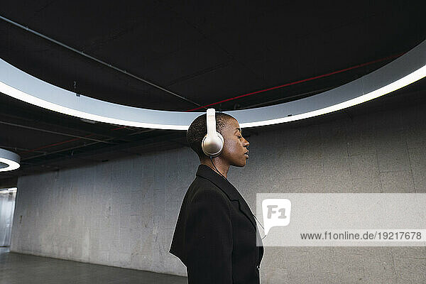 Young woman listening music on headphones in parking garage