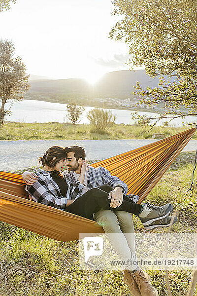 Boyfriend and girlfriend spending leisure time sitting in hammock