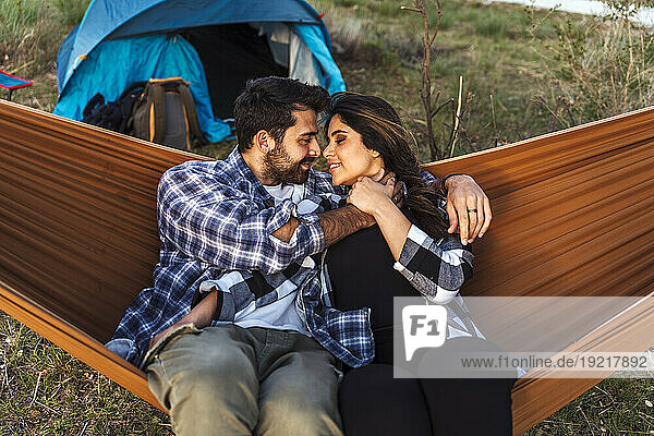 Romantic couple relaxing face to face in hammock