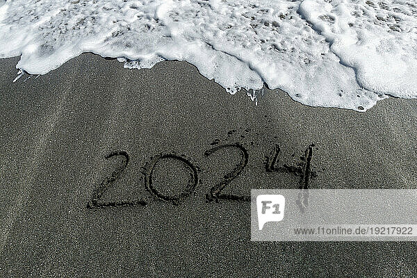 2024 handwritten in black beach sand