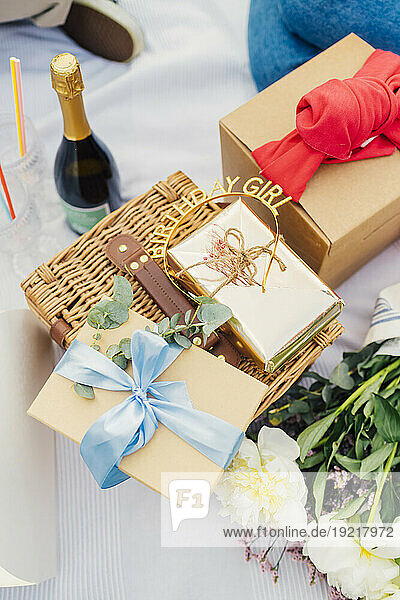 Birthday gift boxes on picnic basket with wine bottle and bouquet of flowers