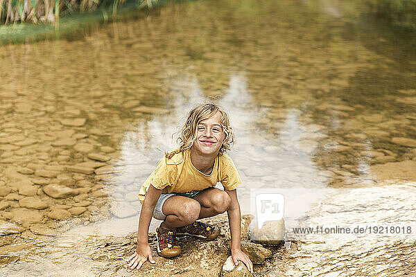 Smiling boy crouching near river