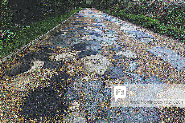 . English road with potholes and bitumen repair