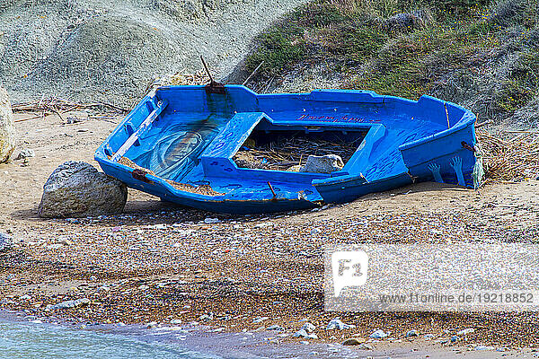 Europe,  Italy,  Sicily,  abandoned migrant boat painted blue on a beach