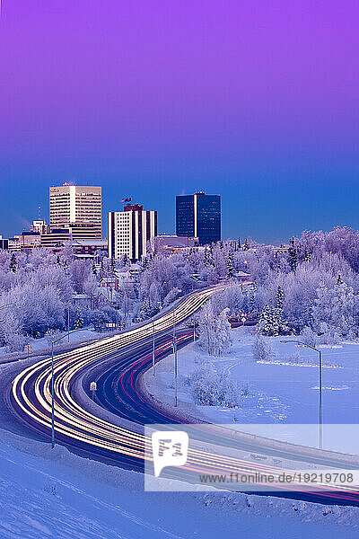 Alpenglow Over The Anchorage Skyline With The Lights From Traffic On Minnesota Blvd. In The Foreground During Winter  Southcentral Alaska